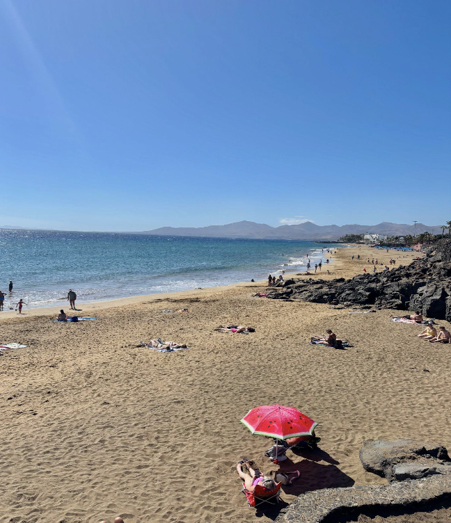 A tourist lounges on an empty beach of Puerta del Carmen on a February day
